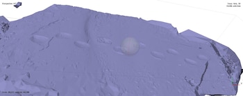 Modelo tridimensional de una superficie rocosa con depresiones redondeadas en fila, una esfera en el centro e indicadores de coordenadas espaciales