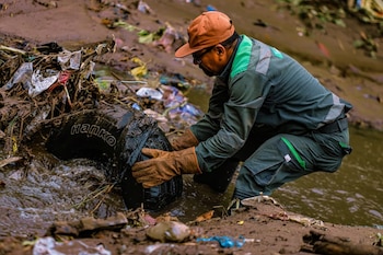 Un trabajador municipal retira desechos sólidos y llantas de un río en San Salvador Centro, como parte de las jornadas de limpieza (Cortesía @DesechoSolidos).