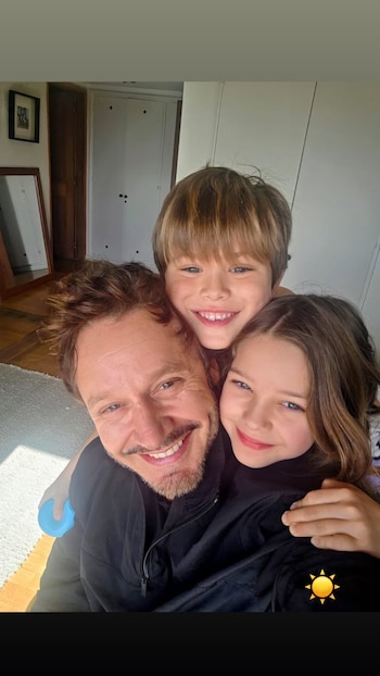 Primer plano de Benjamín Vicuña junto a un niño y una niña que sonríen mirando a la cámara