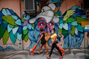 Mujeres con tapabocas caminan frente