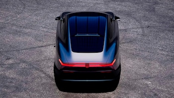 Vista superior de un automóvil prototipo de color oscuro con techo de tono azulado y faros traseros rojos encendidos sobre asfalto