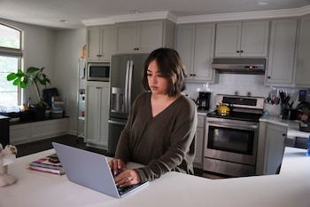 Lisa Green checks the Ollie Assistant from her computer at her home in Kansas City, Kansas, on October 3, 2026. Even as alarm grows over the risks, families are embracing bots and agents to tackle the spiraling administrative tasks of modern child rearing. (Arin Yoon/The New York Times)