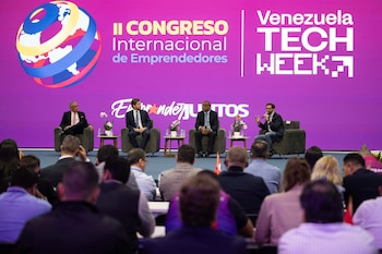 Cuatro hombres en un panel de discusión en un escenario morado, frente a una audiencia. El fondo incluye logos de "Congreso de Emprendedores" y "Venezuela Tech Week"