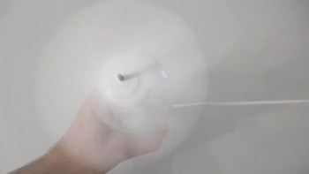 Vista superior de una mano sosteniendo un recipiente plástico transparente lleno de vapor blanco