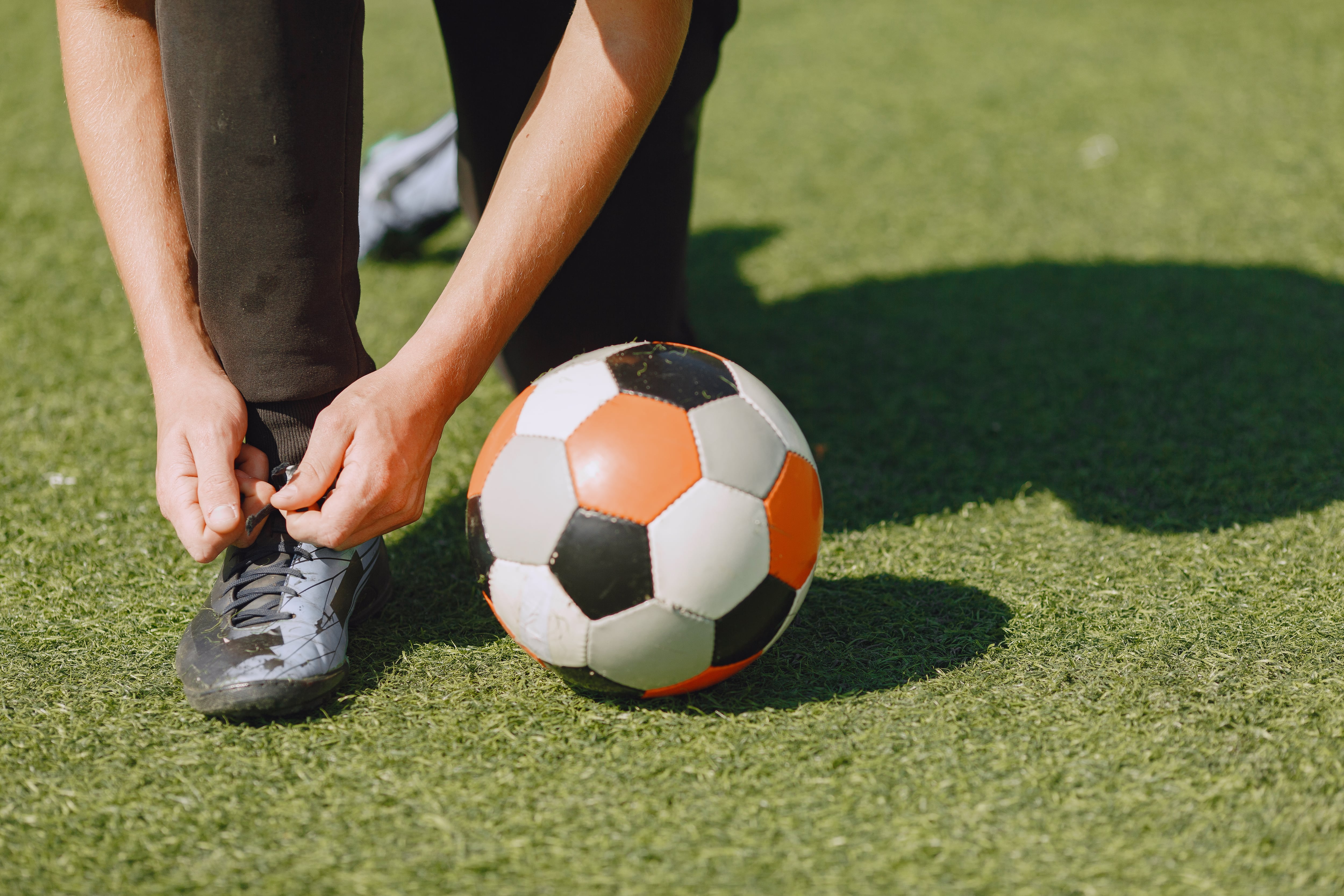 Un hombre atándose las zapatillas de deporte antes de jugar al fútbol (Freepik)