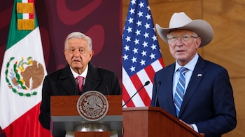 Dos hombres en sendos podios. Uno viste saco oscuro y corbata rosa, junto a la bandera de México. El otro lleva sombrero, traje azul y corbata, junto a la bandera de Estados Unidos.