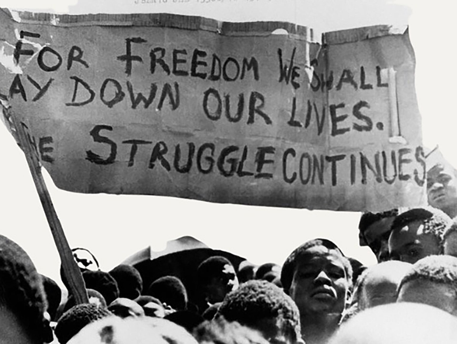 Una pancarta se sostiene en alto sobre unos estudiantes negros en Johannesburgo, Sudáfrica, en el municipio de Soweto, donde se manifestaron tras el funeral de un estudiante negro de 16 años que murió en prisión, el 18 de octubre de 1976 (AP)