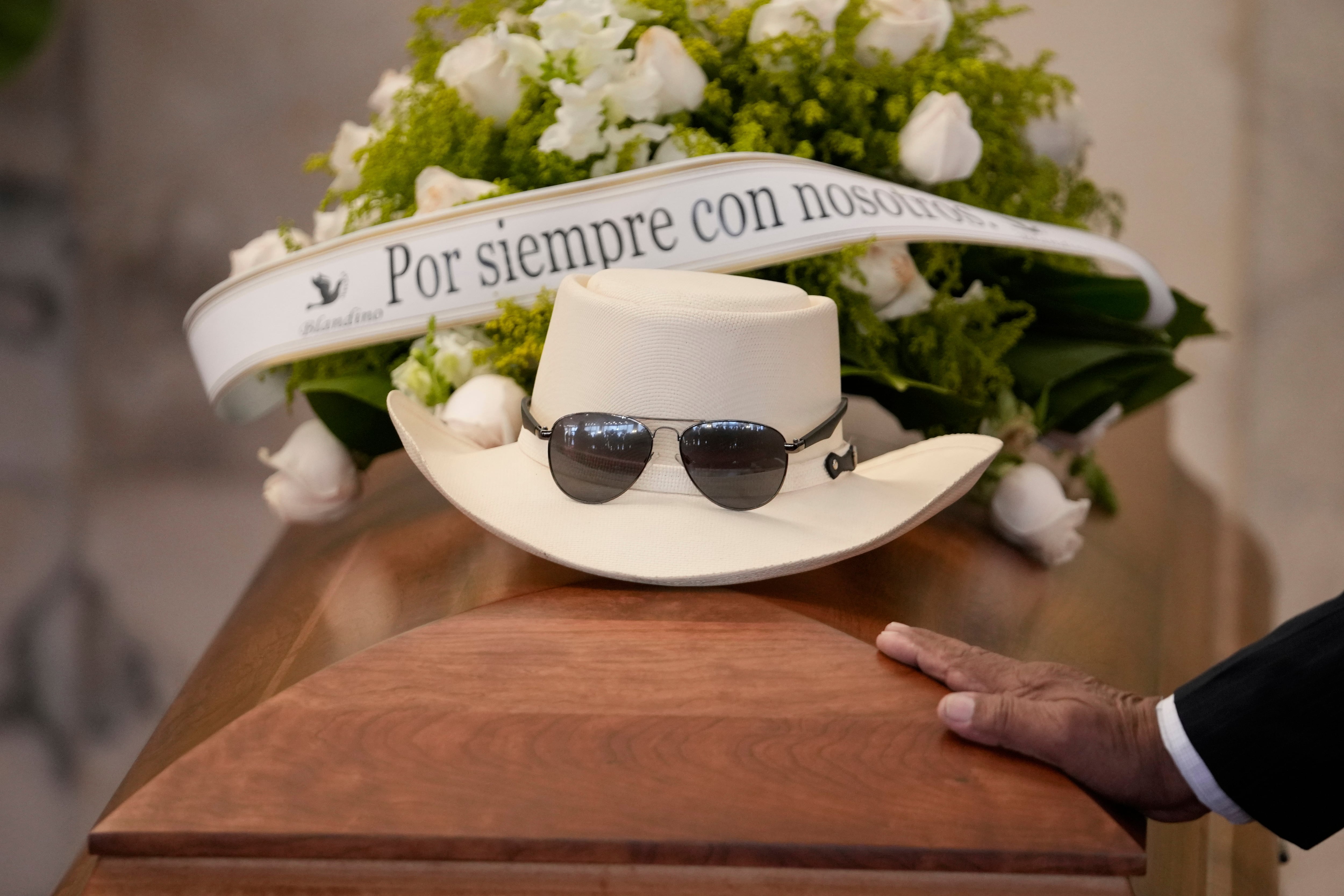 El sombrero y las gafas de sol del cantante dominicano Rubby Perez, fallecido en el derrumbe del techo del club nocturno Jet Set mientras daba un concierto de merengue, sobre su ataúd durante su velorio en el Teatro Nacional Eduardo Brito en Santo Domingo, República Dominicana, el jueves 10 de abril de 2025. (AP Foto/Matias Delacroix)
