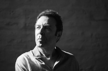 Retrato en blanco y negro de Armand Amar. Hombre de mediana edad, cabello oscuro, mira a la izquierda con expresión seria, iluminado por fuerte contraluz