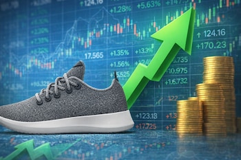 Una zapatilla gris con suela blanca, una flecha verde ascendente, pilas de monedas de oro y gráficos bursátiles en un fondo azul borroso.