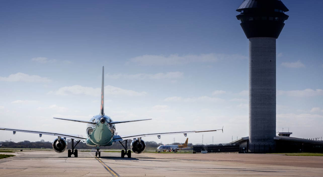 Un avión comercial maniobra en la pista junto a la torre de control en un aeropuerto. (Manchester Airports Group)