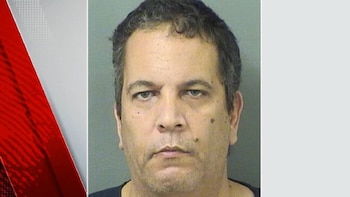 Primer plano de un hombre de mediana edad con cabello oscuro y ojos claros mirando fijamente a la cámara, sobre un fondo liso y claro