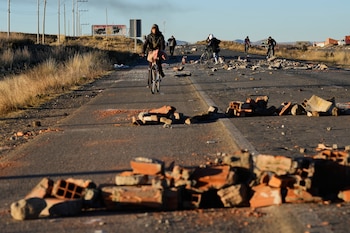 Varias personas rodean las barricadas levantadas por los manifestantes en la carretera que conecta La Paz con Oruro, cerca de El Alto, Bolivia, el sábado 16 de mayo de 2026. (AP Foto/Juan Karita)