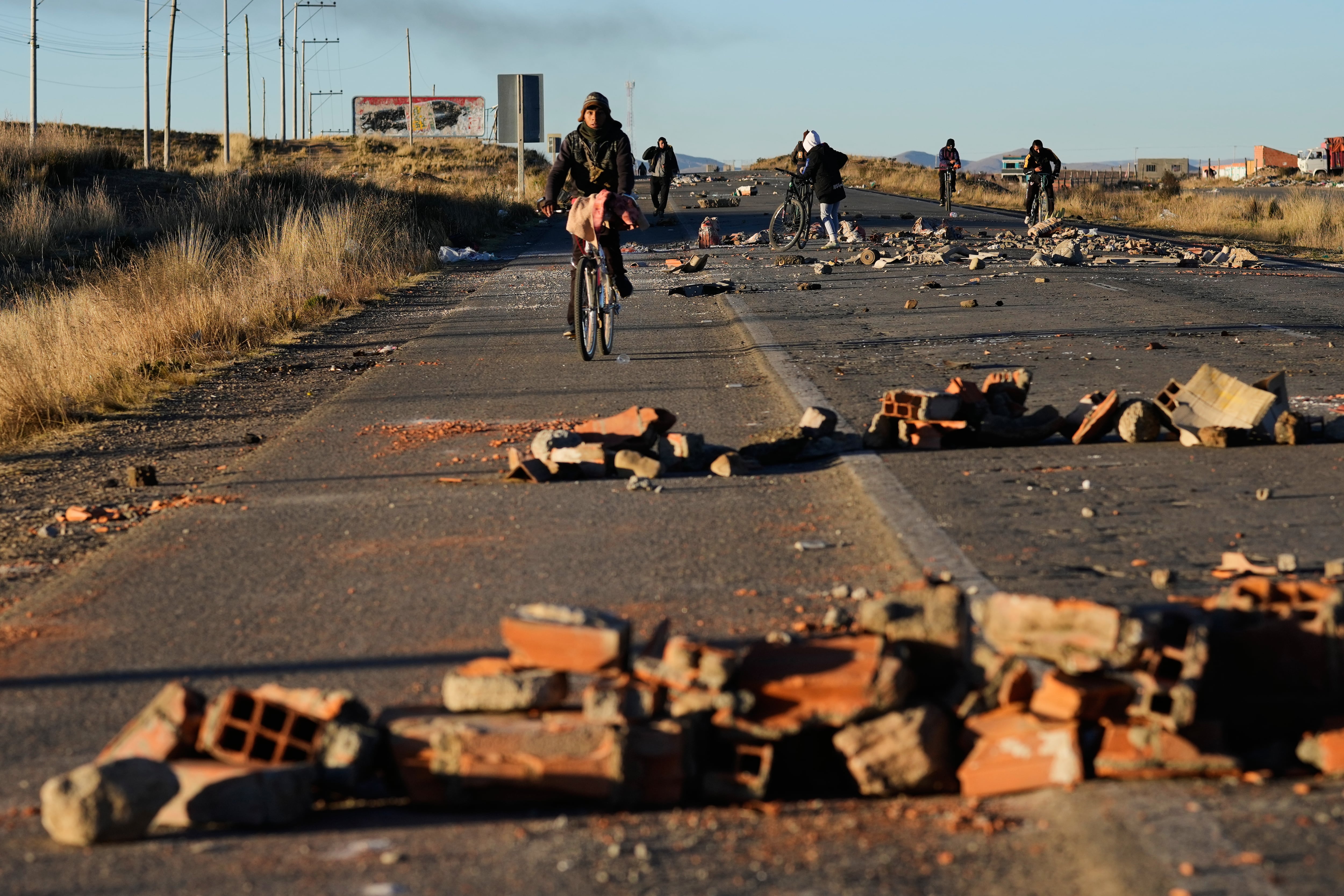 Varias personas rodean las barricadas levantadas por los manifestantes en la carretera que conecta La Paz con Oruro, cerca de El Alto, Bolivia (AP/Juan Karita)
