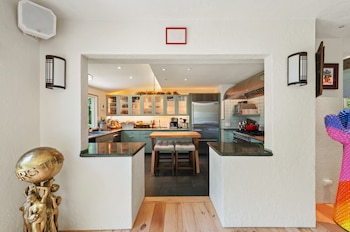 Cocina moderna con gabinetes azules, electrodomésticos de acero inoxidable y una isla de madera, vista a través de un arco. Suelo de madera y azulejo