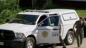 Una camioneta pickup blanca de aplicación de la ley con luces de emergencia en el techo, un escudo de Ohio y dos agentes uniformados