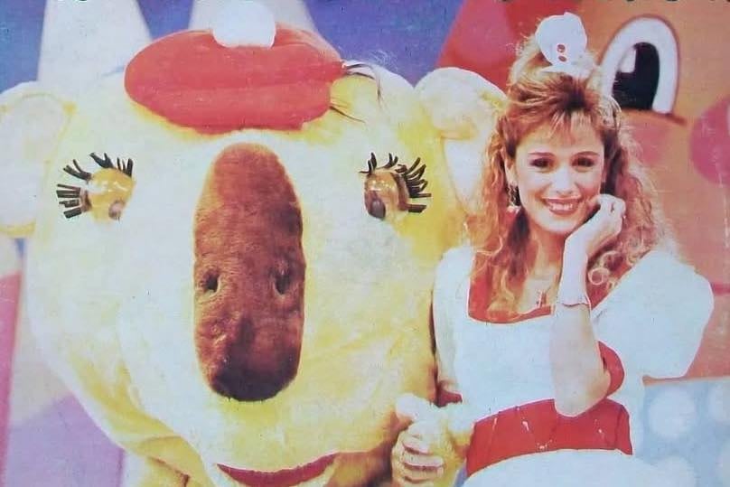 Flavia Palmiero sonríe con su mano en la barbilla junto a Pelín, la famosa mascota