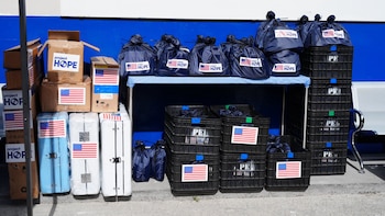Cajas de cartón, bolsas azules con el logotipo de Project HOPE y cestas de plástico con calcomanías de la bandera de Estados Unidos
