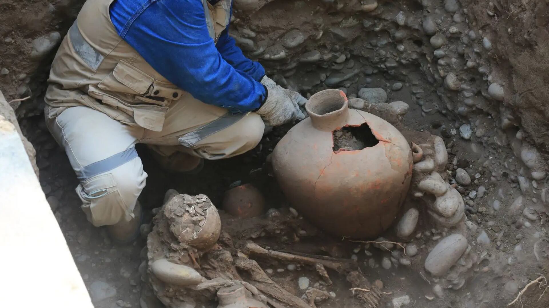 Un arqueólogo o trabajador examina cuidadosamente un entierro prehispánico de la cultura Blanco sobre Rojo en San Isidro, que incluye un esqueleto y ajuares funerarios de hasta 2.000 años de antigüedad. (Foto: Agencia Andina)