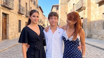 Tres personas están de pie en una calle empedrada entre edificios antiguos de piedra, sonriendo hacia el centro.