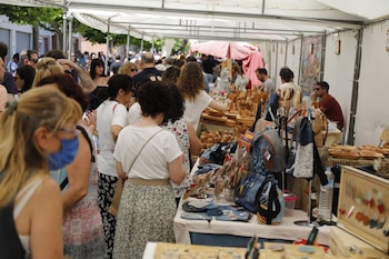 Gente en varios puestos de mercado revisando la artesanía
