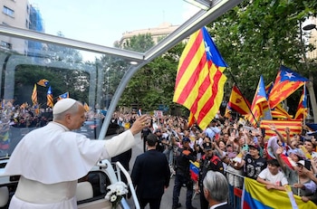 Varias personas ondean banderas independentistas de Cataluña durante el recorrido del papa por las calles de Barcelona.
