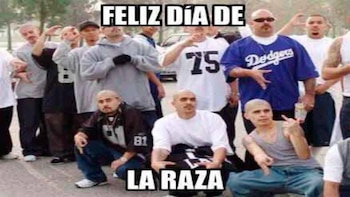 Un grupo de hombres posa en la calle bajo el texto en mayúsculas blancas que indica «FELIZ DÍA DE LA RAZA»