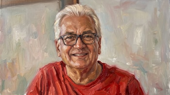 Pintura al óleo del rostro y torso de un hombre mayor con pelo blanco, gafas de pasta oscura, sonrisa y camiseta de color rojo.