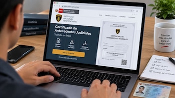 Una persona utiliza una computadora portátil que muestra la plataforma web del Instituto Nacional Penitenciario de Perú en un escritorio