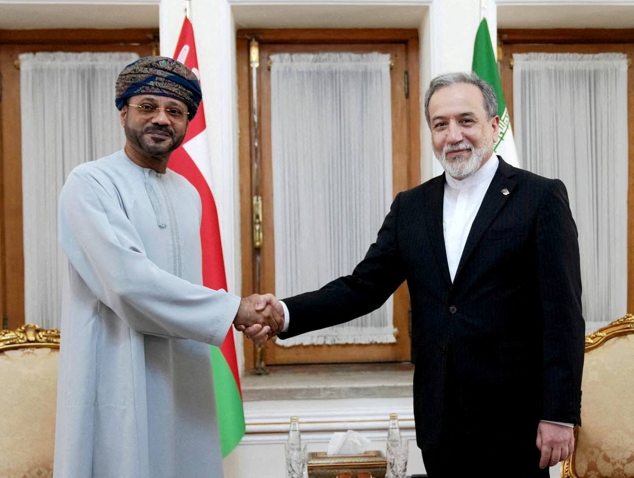 Los ministros de Relaciones Exteriores de Irán, Abbas Araghchi (dcha), y Omán, Sayyid Badr al-Busaidi, se saludan durante un encuentro en Teherán, Irán (REUTERS)