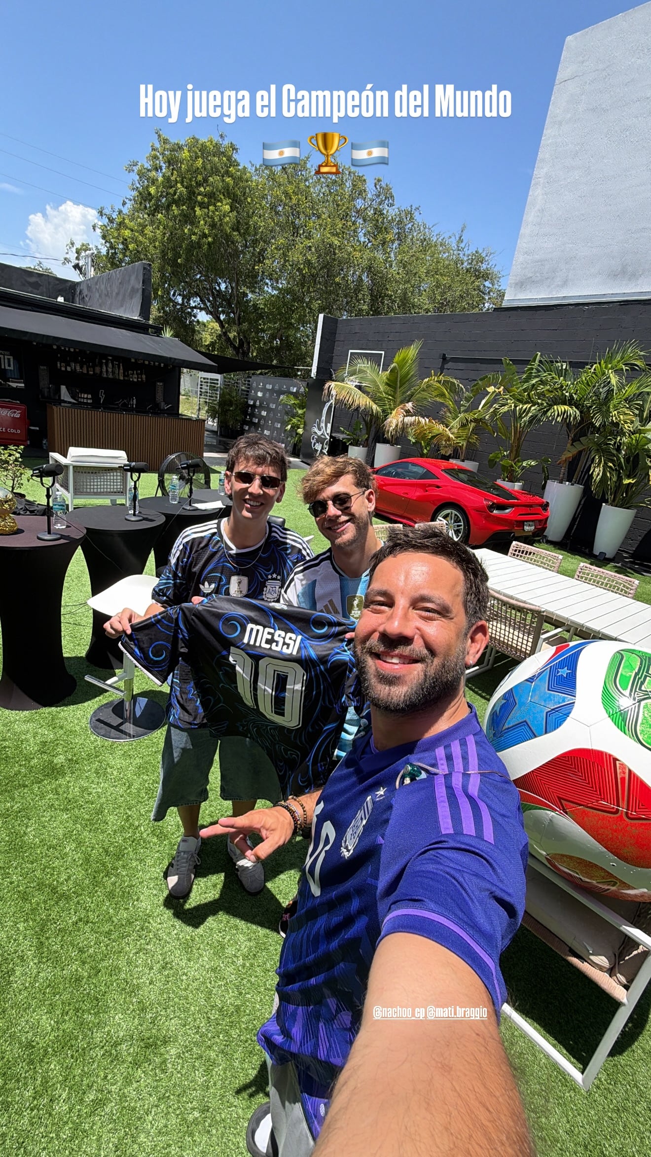 Cachete Sierra y Nacho Castañeras posan con camisetas de la selección argentina junto a un amigo, en un evento al aire libre en Miami.