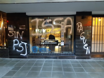 Calle urbana, edificio moderno, grupo de personas, banner Sindicato Hotelero Gastronómicos, letreros, megáfono, persona con disfraz, vehículos