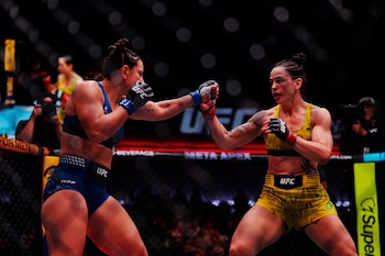 Dos peleadoras de artes marciales mixtas combaten dentro de una jaula octagonal con vestimenta deportiva y guantes