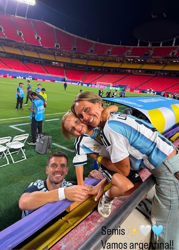 Un hombre, una mujer y un niño con camisetas de la Selección Argentina sonríen a cámara en la tribuna de un estadio de fútbol