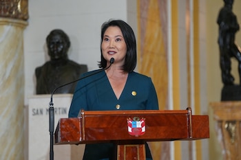 Keiko Fujimori habla ante un podio de madera con el escudo de Perú frente a un busto de San Martín en un salón