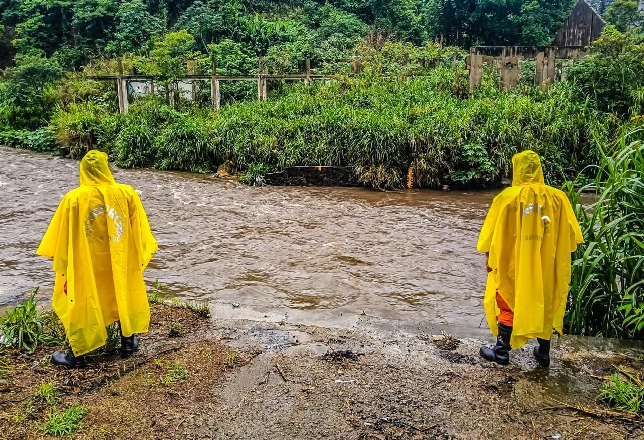 Personal de emergencia supervisa el caudal de un río crecido tras las intensas lluvias provocadas por la depresión tropical Cristina en El Salvador (Cortesía Protección Civil).