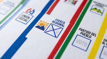 Cédula de sufragio impresa con columnas de colores, símbolos de partidos políticos y una marca de cruz azul en el recuadro de voto.