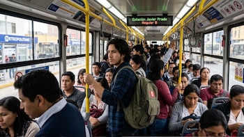 Interior de un autobús abarrotado con pasajeros de pie y sentados, barras amarillas de sujeción y un cartel digital con la estación Javier Prado