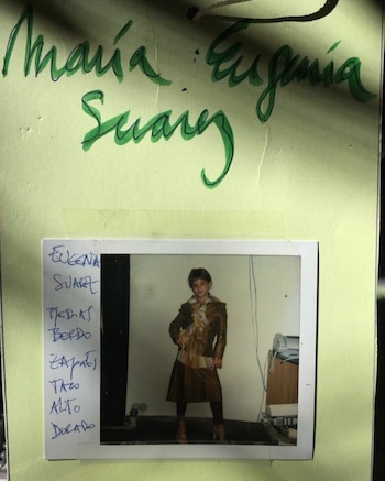Hoja con el nombre María Eugenia Suárez en tinta verde sobre una fotografía instantánea de una niña junto a anotaciones manuscritas de vestuario
