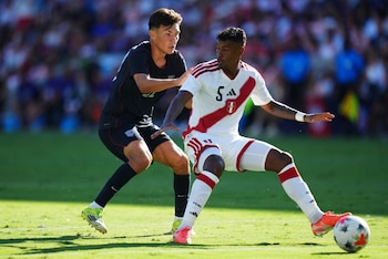 Dos futbolistas disputan el balón en una cancha de césped durante un partido entre las selecciones de Perú y Estados Unidos