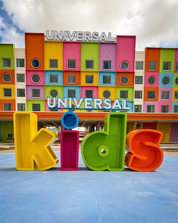 Vista frontal del Parque Temático Universal Kids con un edificio de fachada multicolor y grandes letras 3D que forman "Kids" en primer plano