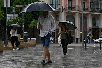 Varias personas caminan bajo la lluvia en Palma este miércoles. (Miquel A. Borràs/EFE)
