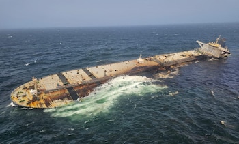 Vista aérea de un petrolero semisumergido con la proa levantada y la popa hundida en el mar, con óxido y daños visibles en el casco