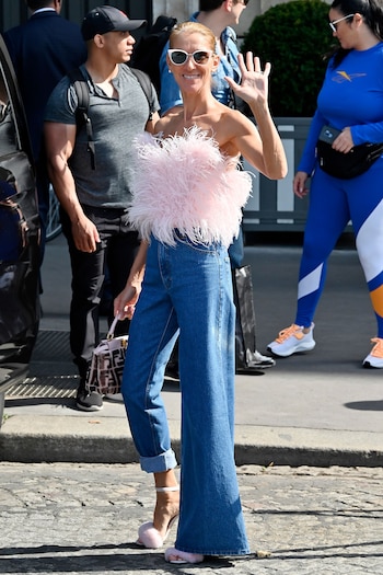 El top strapless de plumas rosas combinado con pantalón vaquero de tiro alto y gafas blancas grandes revela el costado lúdico y experimental del estilo urbano de Céline Dion (Grosby Group)