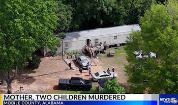 Vista aérea de una casa rodante blanca rodeada de árboles, con varios vehículos y personas, posiblemente investigadores, en el exterior de la propiedad