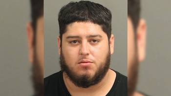 Fotografía de frente de un hombre con cabello oscuro, barba alrededor de la mandíbula y camiseta negra sobre fondo claro