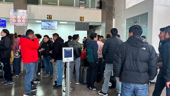 Multitud de pasajeros esperando en una terminal de aeropuerto, con mostradores de facturación numerados 17 y 18, carteles de Andes, logo de CORPAC y equipaje visible