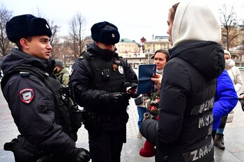 Police officers check documents of relatives of Russian soldiers, taking part in the so-called "special military operation" in Ukraine, as they gather to lay flowers at the Tomb of the Unknown Soldier in Moscow on December 23, 2023. (Photo by Olga MALTSEVA / AFP)