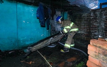 Un miembro del Cuerpo de Bomberos realiza labores de remoción y enfriamiento tras el incendio estructural registrado en una vivienda de San Juan Opico, La Libertad (Cortesía: Cuerpo de Bomberos).
