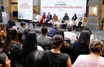 Panel de expertos sentados en un escenario elevado, frente a un público. Detrás del panel, un gran cartel blanco anuncia 'Ley Trasciende: El Camino hacia la Muerte Digna en México'